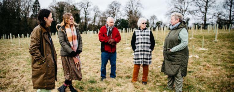 Group photo of five people talking in a newly planted woodland area. Photo credit Alex Turner Photography