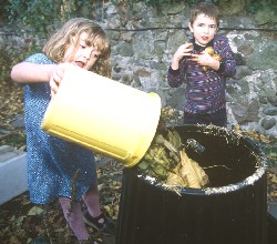 young girl and boy putting food into a compost bin